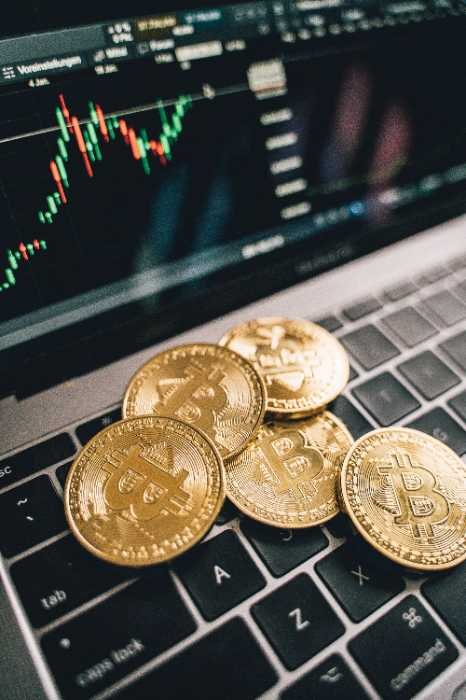 Bitcoin coins on a laptop keyboard in front of a price chart
