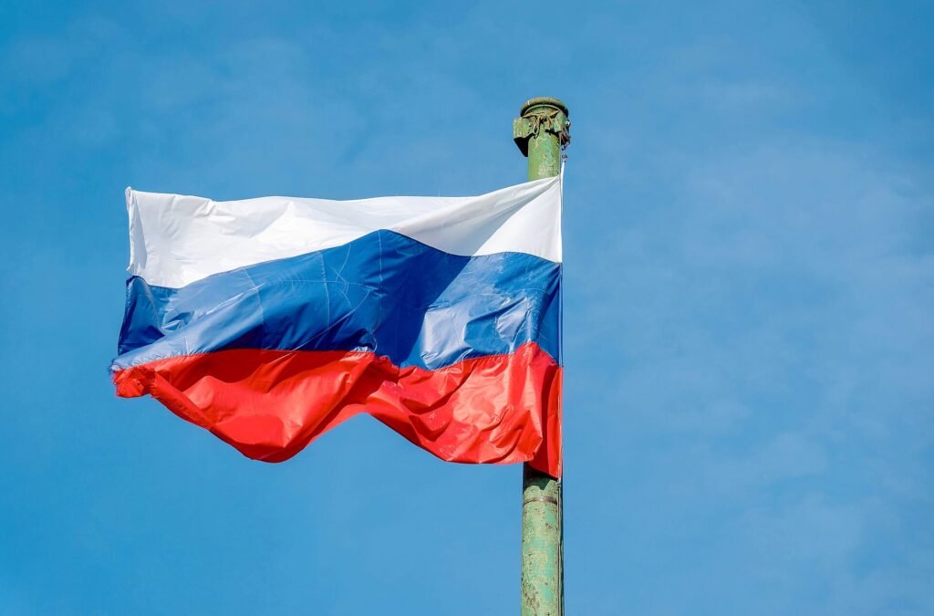 Russian flag on a cast-iron flagpole against a blue sky